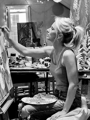 Black and white photo of a woman sitting on a chair with a paint palette in her lap painting a large canvas.